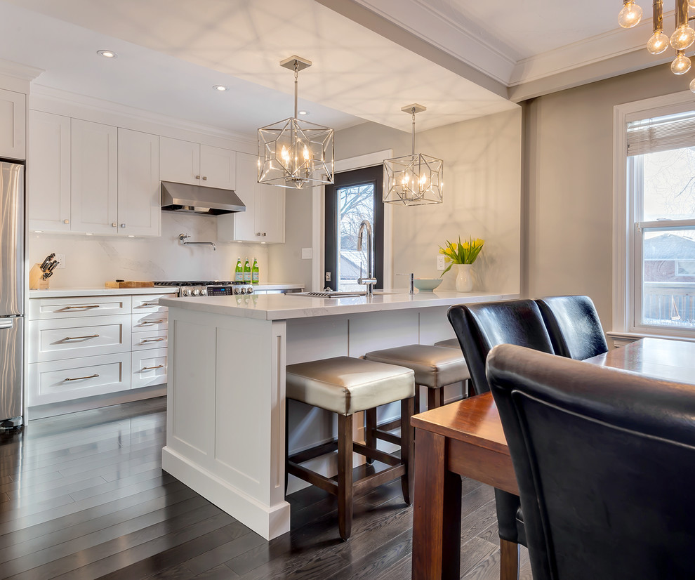 Inspiration for a small transitional galley dark wood floor eat-in kitchen remodel in Toronto with an undermount sink, shaker cabinets, white cabinets, quartz countertops, white backsplash, stone slab backsplash, stainless steel appliances and an island
