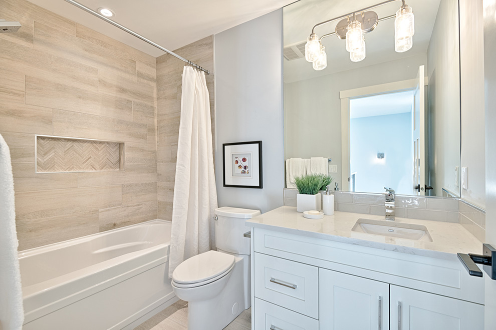 Inspiration for a mid-sized arts and crafts kids bathroom in Calgary with shaker cabinets, white cabinets, a drop-in tub, a shower/bathtub combo, a one-piece toilet, gray tile, ceramic tile, grey walls, an undermount sink, quartzite benchtops, a shower curtain and porcelain floors.