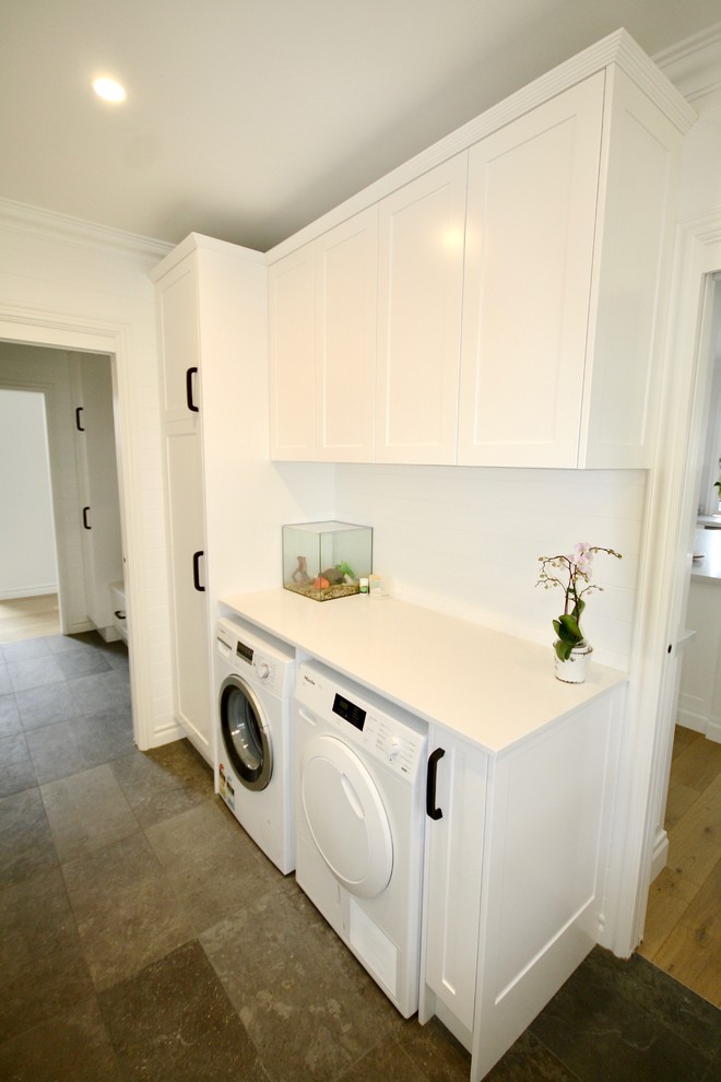 This is an example of a mid-sized transitional u-shaped dedicated laundry room in Sydney with an undermount sink, shaker cabinets, white cabinets, quartz benchtops, white walls, porcelain floors, a side-by-side washer and dryer and brown floor.