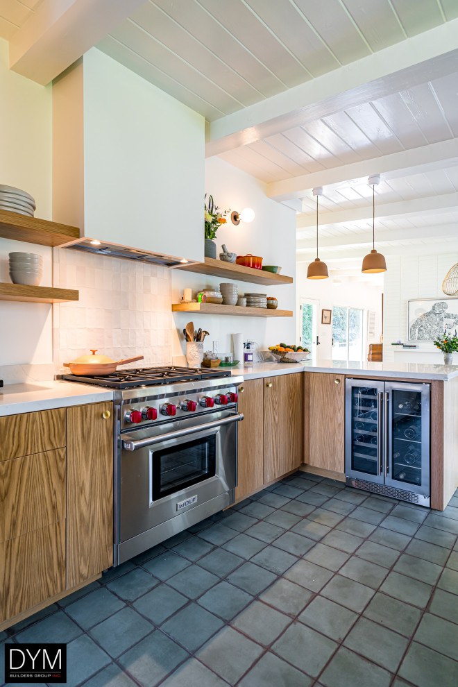 Design ideas for a country u-shaped eat-in kitchen in Los Angeles with a drop-in sink, flat-panel cabinets, medium wood cabinets, solid surface benchtops, white splashback, coloured appliances, ceramic floors, a peninsula, grey floor, white benchtop and timber.