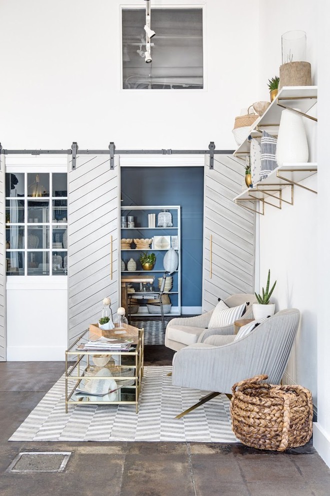 Photo of an industrial living room in Orange County with white walls and brown floor.