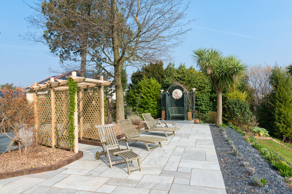 Design ideas for a large transitional patio in Devon with natural stone pavers and no cover.