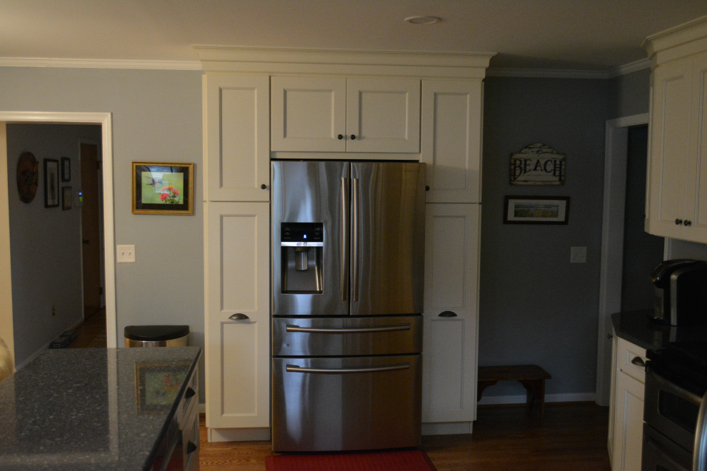 Mid-sized transitional u-shaped dark wood floor and brown floor eat-in kitchen photo with a farmhouse sink, shaker cabinets, beige cabinets, granite countertops, gray backsplash, mosaic tile backsplash, stainless steel appliances, a peninsula and black countertops