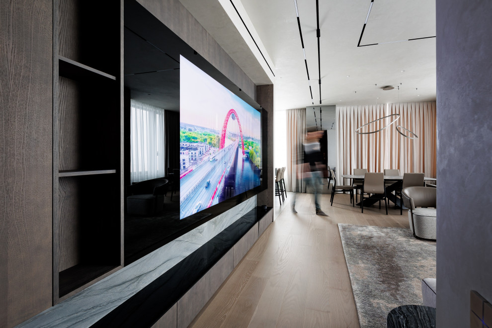 На фото: большая открытая гостиная комната в современном стиле с музыкальной комнатой, серыми стенами, паркетным полом среднего тона и скрытым телевизором