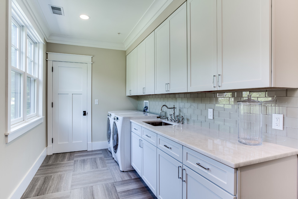 This is an example of a large arts and crafts galley dedicated laundry room in DC Metro with a drop-in sink, shaker cabinets, white cabinets, quartz benchtops, beige walls, ceramic floors and a side-by-side washer and dryer.