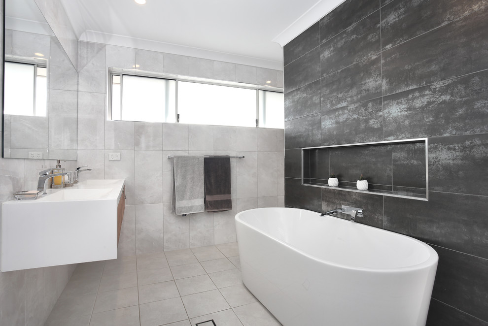 Design ideas for a contemporary bathroom in Sydney with flat-panel cabinets, white cabinets, a freestanding tub, gray tile, grey walls, a wall-mount sink, grey floor and white benchtops.