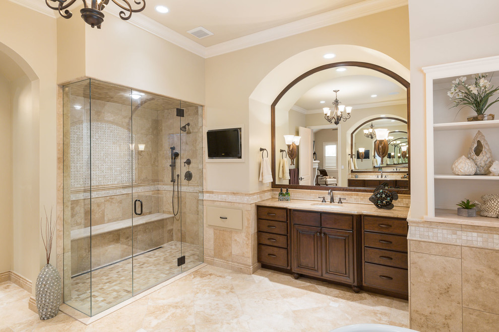Design ideas for a large country master bathroom in Denver with raised-panel cabinets, dark wood cabinets, a corner shower, beige walls, an undermount sink, a hinged shower door, a freestanding tub, a two-piece toilet, beige tile, travertine, travertine floors, limestone benchtops, beige floor and beige benchtops.