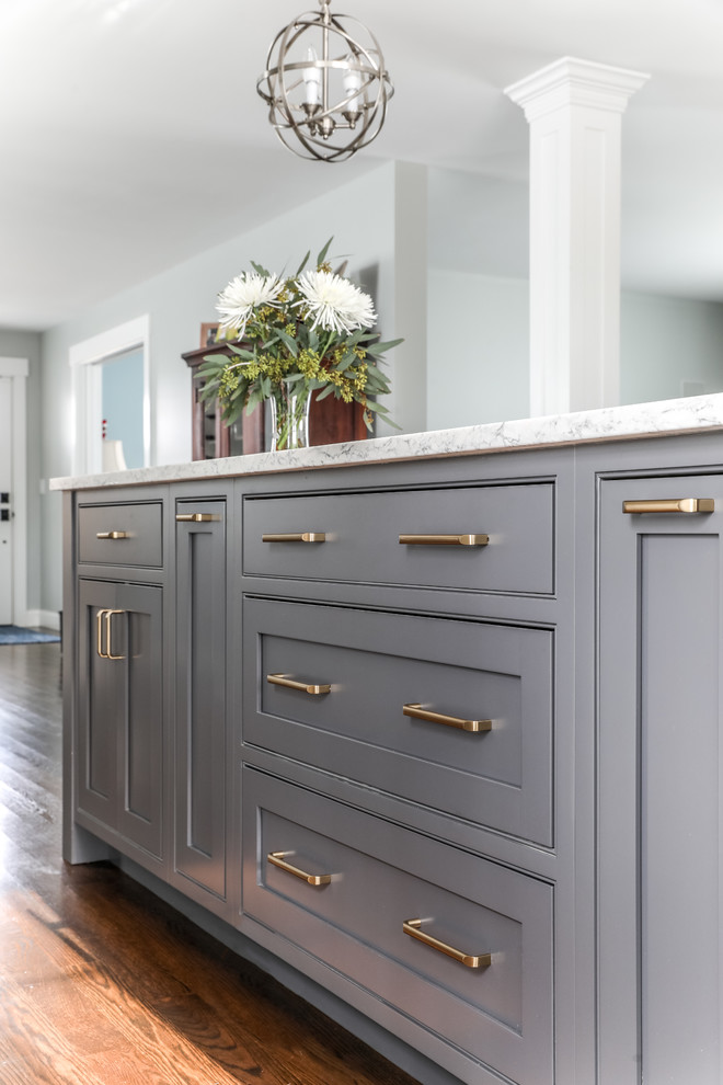 Eat-in kitchen - transitional l-shaped medium tone wood floor and brown floor eat-in kitchen idea in Boston with a farmhouse sink, beaded inset cabinets, white cabinets, quartz countertops, white backsplash, subway tile backsplash, stainless steel appliances, an island and gray countertops