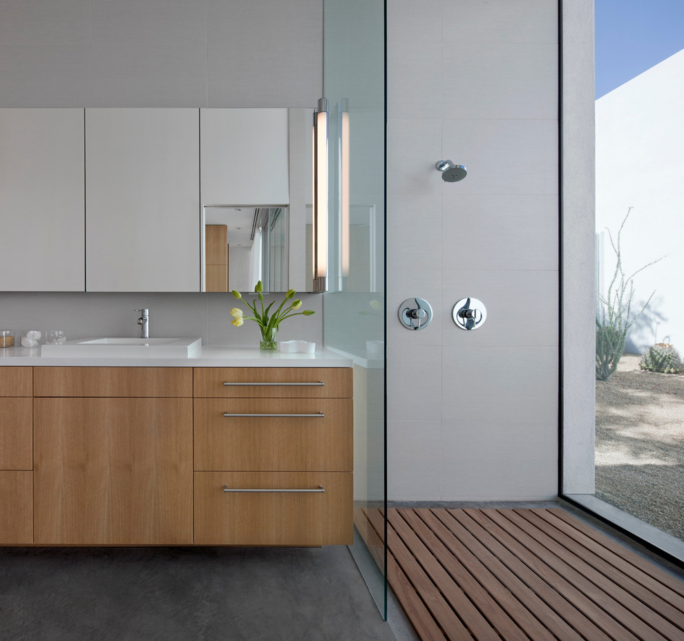 This is an example of a small contemporary master bathroom in Other with flat-panel cabinets, light wood cabinets, an open shower, white tile, porcelain tile, white walls, concrete floors, solid surface benchtops, a drop-in sink and an open shower.