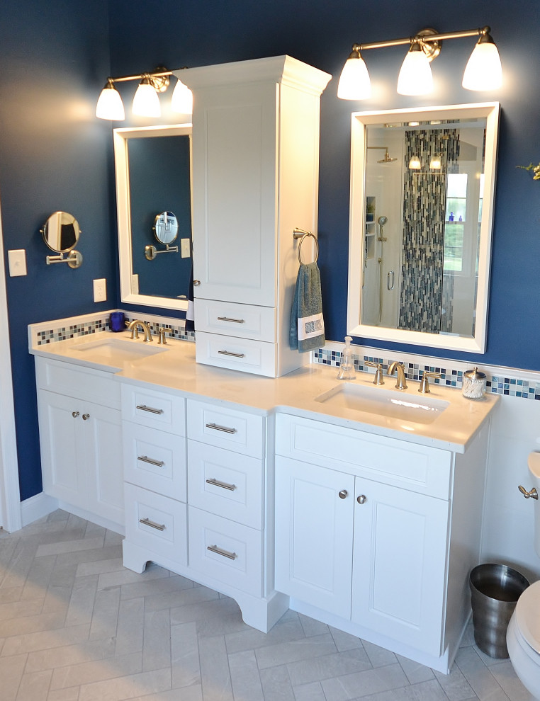Photo of an expansive transitional master bathroom in Philadelphia with recessed-panel cabinets, white cabinets, a freestanding tub, a corner shower, a one-piece toilet, blue tile, mosaic tile, blue walls, ceramic floors, an undermount sink, engineered quartz benchtops, beige floor, a hinged shower door, white benchtops, a shower seat, a double vanity and a built-in vanity.