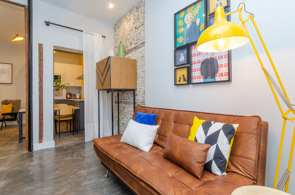 This is an example of a mid-sized industrial open concept family room in Madrid with white walls, concrete floors, a wall-mounted tv and grey floor.