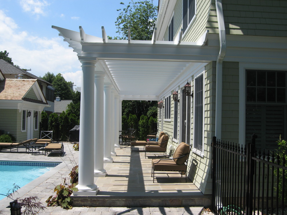 Inspiration for a large traditional backyard verandah in New York with natural stone pavers and a pergola.