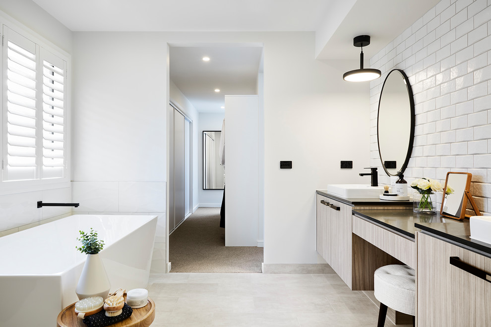 Design ideas for a modern master bathroom in Melbourne with flat-panel cabinets, beige cabinets, a freestanding tub, white tile, white walls, a vessel sink, grey floor and black benchtops.