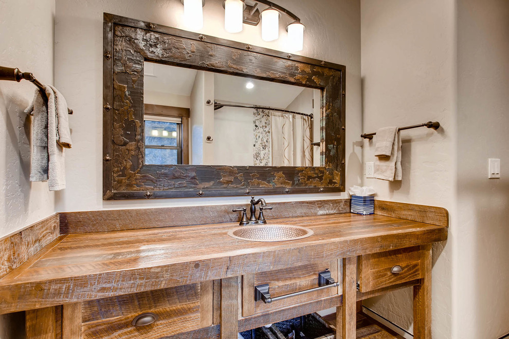 Design ideas for a mid-sized country 3/4 bathroom in Denver with furniture-like cabinets, a corner shower, a two-piece toilet, ceramic floors, a drop-in sink, wood benchtops, grey floor, a hinged shower door and brown benchtops.
