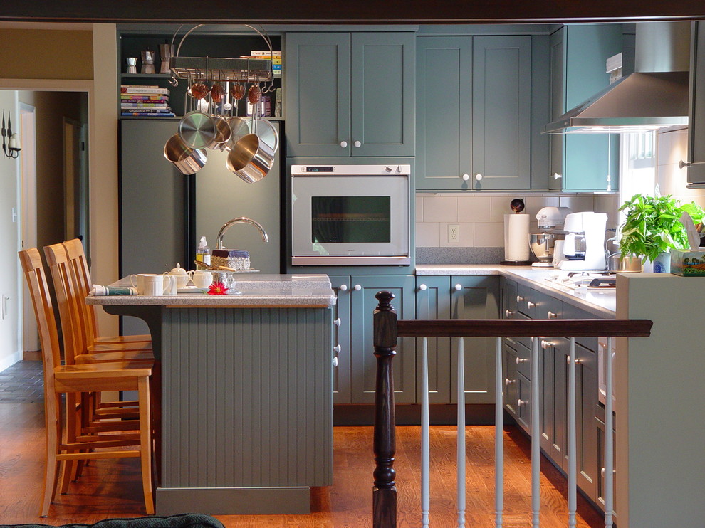 This is an example of a transitional l-shaped kitchen in New York with stainless steel appliances and blue cabinets.