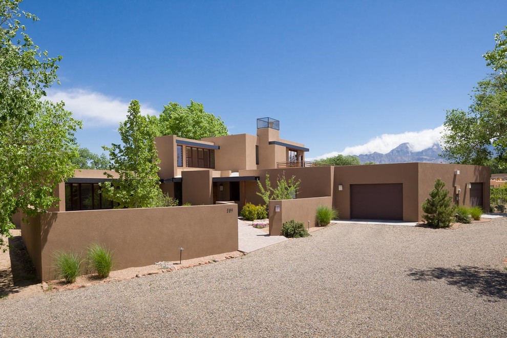 Photo of a large two-storey stucco beige house exterior in Albuquerque with a flat roof and a metal roof.