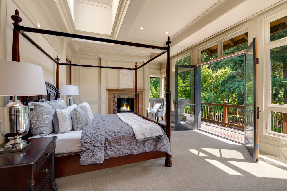 This is an example of a traditional master bedroom in Seattle with beige walls, carpet, a standard fireplace, a stone fireplace surround and beige floor.