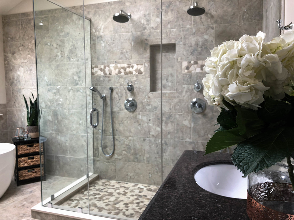 Design ideas for a large transitional master bathroom in Philadelphia with an undermount sink, raised-panel cabinets, dark wood cabinets, granite benchtops, a freestanding tub, a corner shower, a two-piece toilet, gray tile, ceramic tile, beige walls, travertine floors and black benchtops.