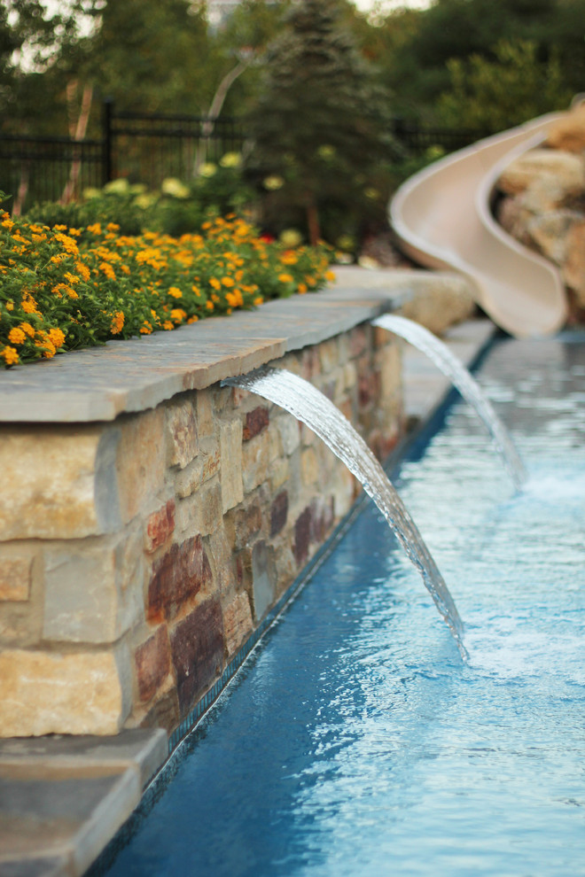 Photo of an eclectic l-shaped natural pool in Kansas City with a water feature.