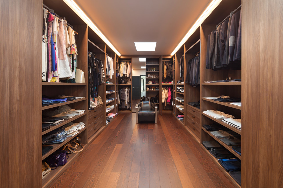 Photo of a large contemporary gender-neutral dressing room in Los Angeles with flat-panel cabinets, medium wood cabinets, medium hardwood floors and brown floor.