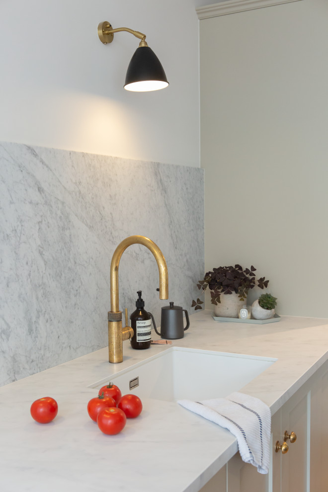 Inspiration for a large modern single-wall kitchen/diner in London with grey cabinets, an island and white worktops.