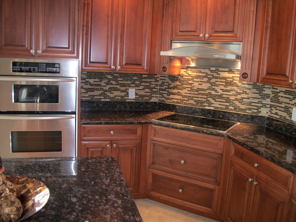 Example of a mid-sized transitional u-shaped travertine floor eat-in kitchen design in Tampa with raised-panel cabinets, medium tone wood cabinets, granite countertops, multicolored backsplash, stainless steel appliances, an island and matchstick tile backsplash