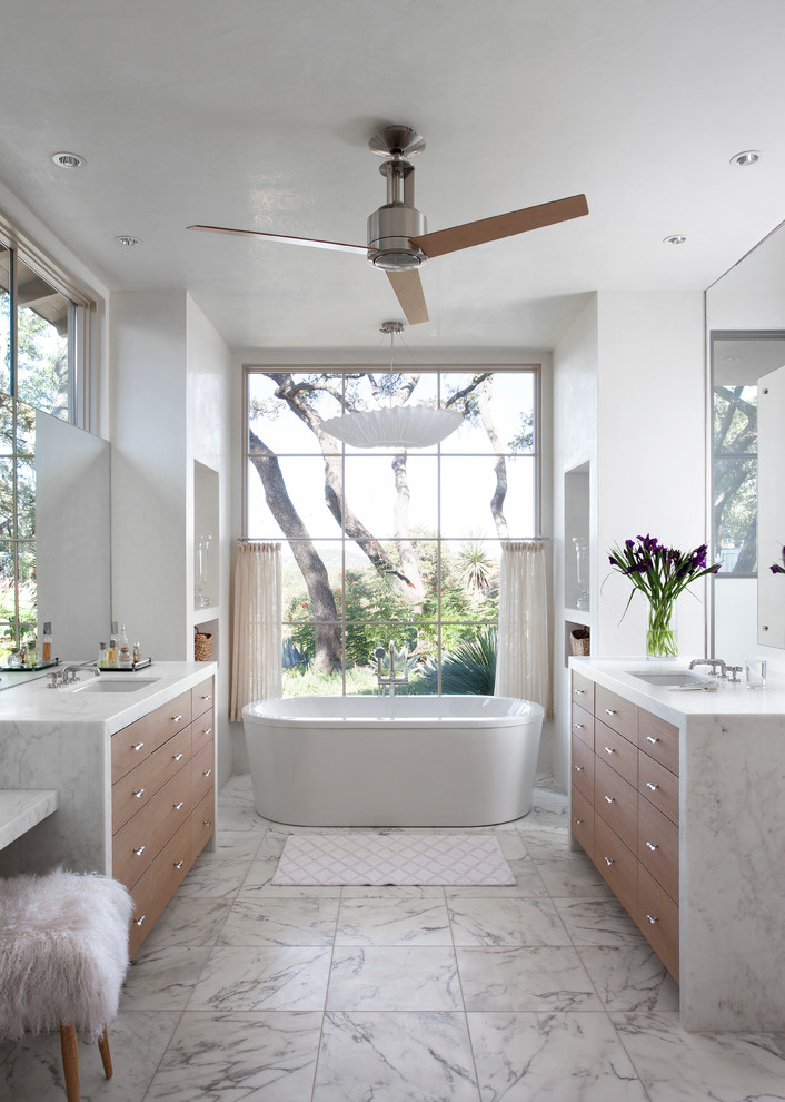 Inspiration for a mediterranean master bathroom in Austin with flat-panel cabinets, medium wood cabinets, a freestanding tub and white walls.