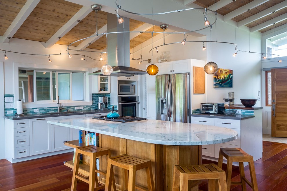 This is an example of a large beach style u-shaped open plan kitchen in Hawaii with a double-bowl sink, shaker cabinets, white cabinets, quartz benchtops, green splashback, glass tile splashback, stainless steel appliances, medium hardwood floors and with island.