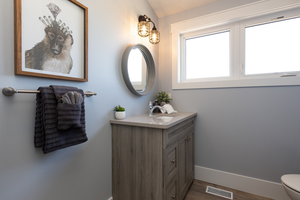 Example of a mid-sized transitional gray floor powder room design in Toronto with shaker cabinets, medium tone wood cabinets, blue walls, an undermount sink, gray countertops and a built-in vanity