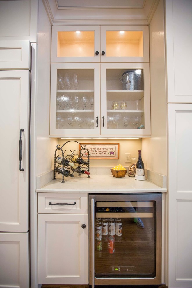 Enclosed kitchen - large transitional l-shaped light wood floor and brown floor enclosed kitchen idea with a farmhouse sink, shaker cabinets, white cabinets, solid surface countertops, white backsplash, porcelain backsplash, stainless steel appliances and an island