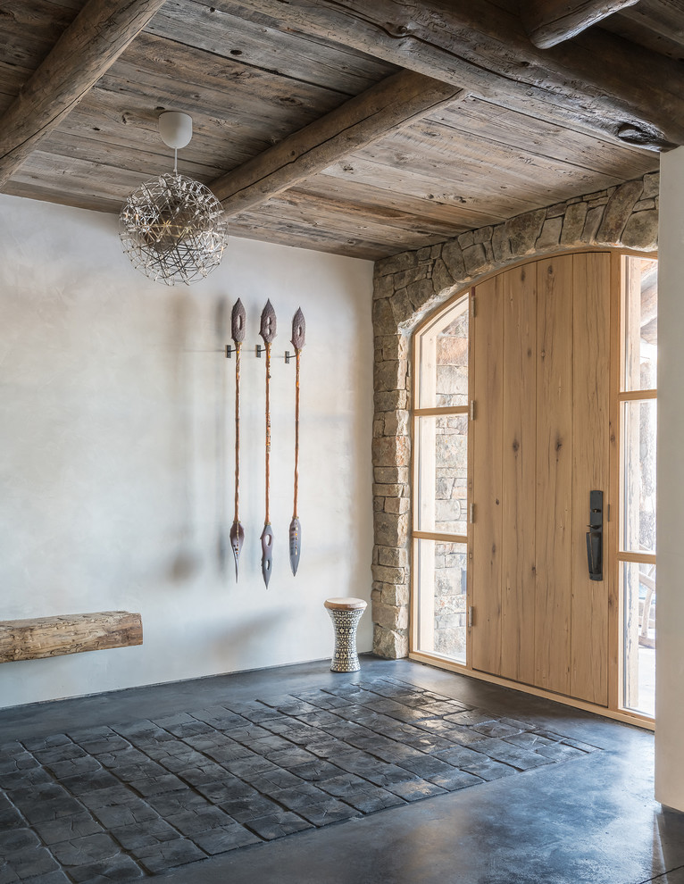 Mountain style concrete floor and black floor single front door photo with white walls and a light wood front door