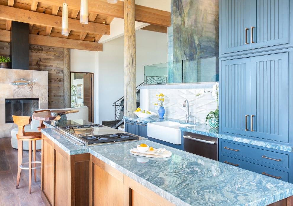 Design ideas for a mid-sized eclectic galley open plan kitchen in San Diego with a farmhouse sink, beaded inset cabinets, blue cabinets, quartzite benchtops, grey splashback, ceramic splashback, stainless steel appliances, medium hardwood floors, with island, brown floor and blue benchtop.