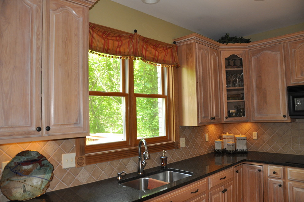 Mid-sized transitional u-shaped medium tone wood floor eat-in kitchen photo in Cincinnati with an undermount sink, raised-panel cabinets, light wood cabinets, granite countertops, beige backsplash, porcelain backsplash, black appliances, green walls and an island
