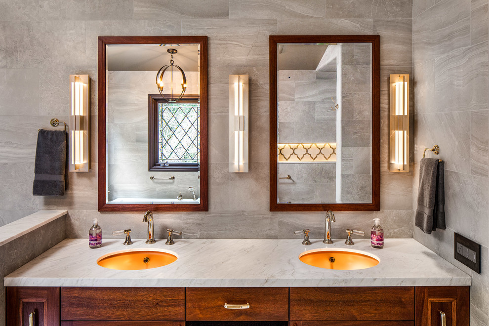 Inspiration for a mid-sized traditional master bathroom in Other with recessed-panel cabinets, dark wood cabinets, a drop-in tub, a curbless shower, a wall-mount toilet, gray tile, porcelain tile, grey walls, marble floors, an undermount sink and marble benchtops.