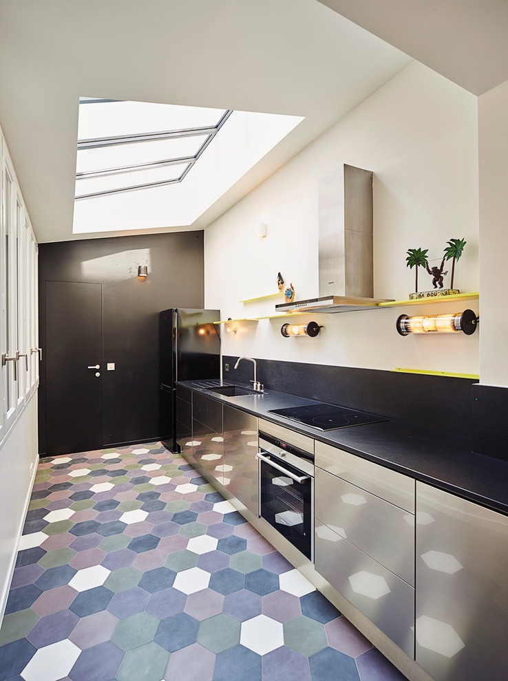 This is an example of a contemporary galley kitchen in Paris with a single-bowl sink, flat-panel cabinets, stainless steel cabinets, black splashback, no island, multi-coloured floor and black appliances.