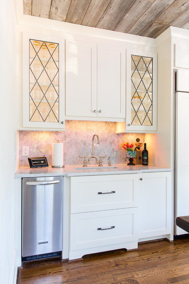 This is an example of a mid-sized country single-wall wet bar in Birmingham with an undermount sink, recessed-panel cabinets, white cabinets, marble benchtops, white splashback, marble splashback, dark hardwood floors, brown floor and white benchtop.