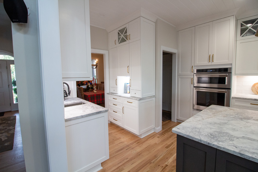 Large l-shaped eat-in kitchen photo with shaker cabinets, white cabinets, granite countertops, an island and white countertops
