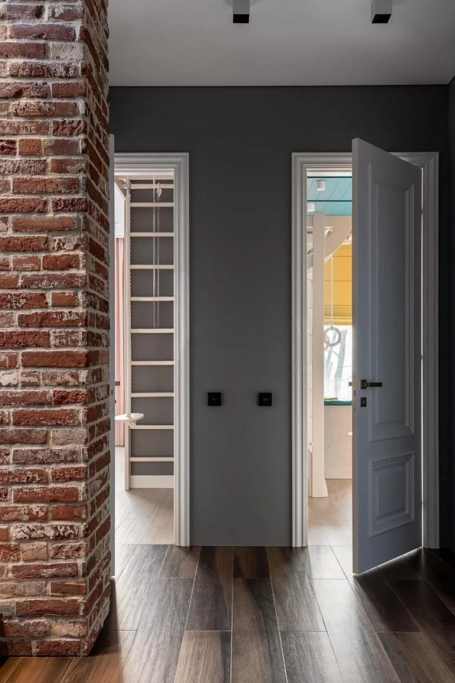 Стильный дизайн: большой, узкий коридор в современном стиле с серыми стенами, полом из керамогранита, коричневым полом и кирпичными стенами - последний тренд