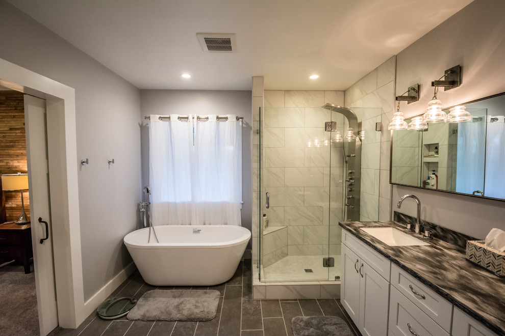 Inspiration for a small transitional master bathroom in Nashville with shaker cabinets, white cabinets, a freestanding tub, a corner shower, a one-piece toilet, gray tile, porcelain tile, grey walls, porcelain floors, an undermount sink, engineered quartz benchtops, black floor and a hinged shower door.