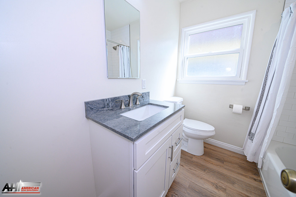 Photo of a small traditional bathroom in Los Angeles with shaker cabinets, white cabinets, an undermount tub, a shower/bathtub combo, a one-piece toilet, white tile, subway tile, white walls, medium hardwood floors, a drop-in sink, quartzite benchtops, beige floor and grey benchtops.