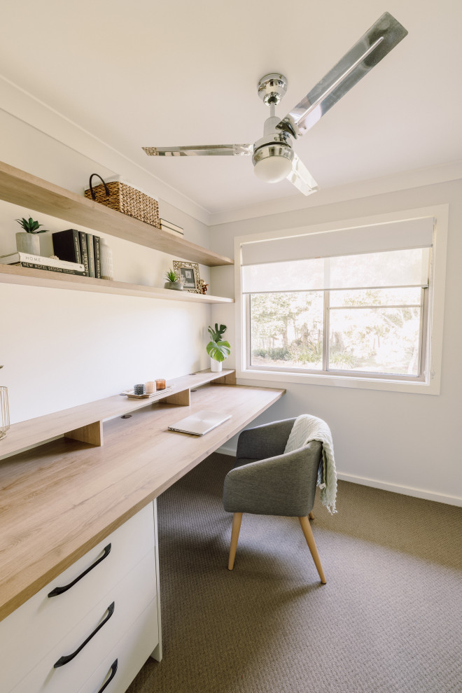 Cette photo montre un petit bureau tendance avec un mur blanc, moquette, un bureau intégré et un sol marron.