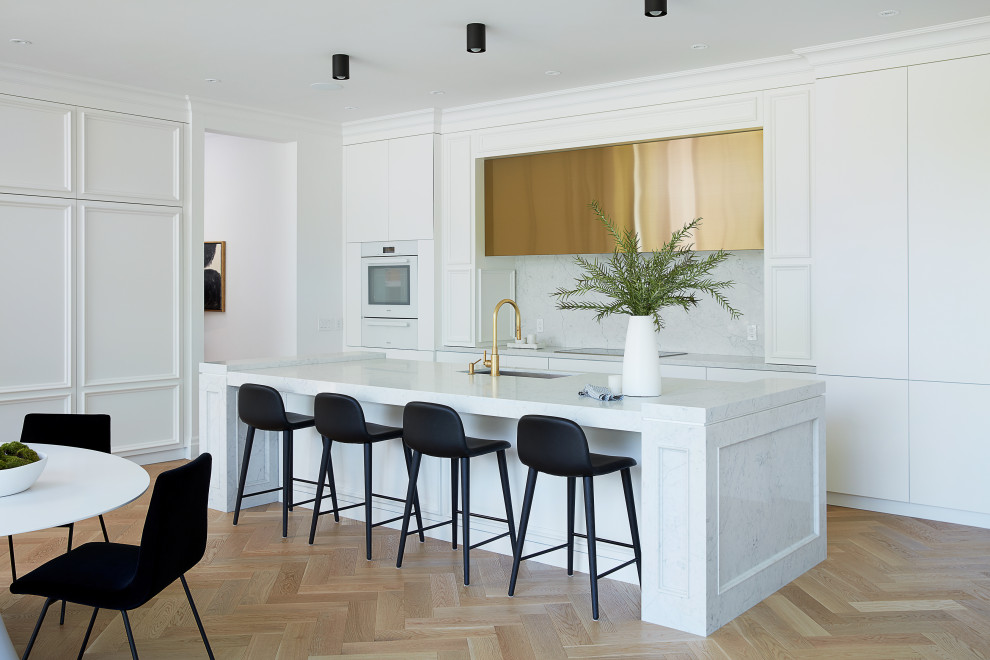 Large l-shaped open plan kitchen in Toronto with an undermount sink, flat-panel cabinets, white cabinets, quartz benchtops, grey splashback, white appliances, with island, beige floor and white benchtop.