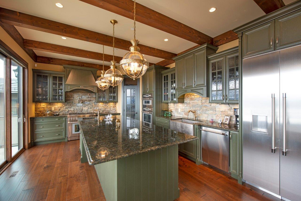 This is an example of a large arts and crafts l-shaped open plan kitchen in Other with a farmhouse sink, glass-front cabinets, green cabinets, granite benchtops, limestone splashback, stainless steel appliances, medium hardwood floors, with island, brown floor and green benchtop.