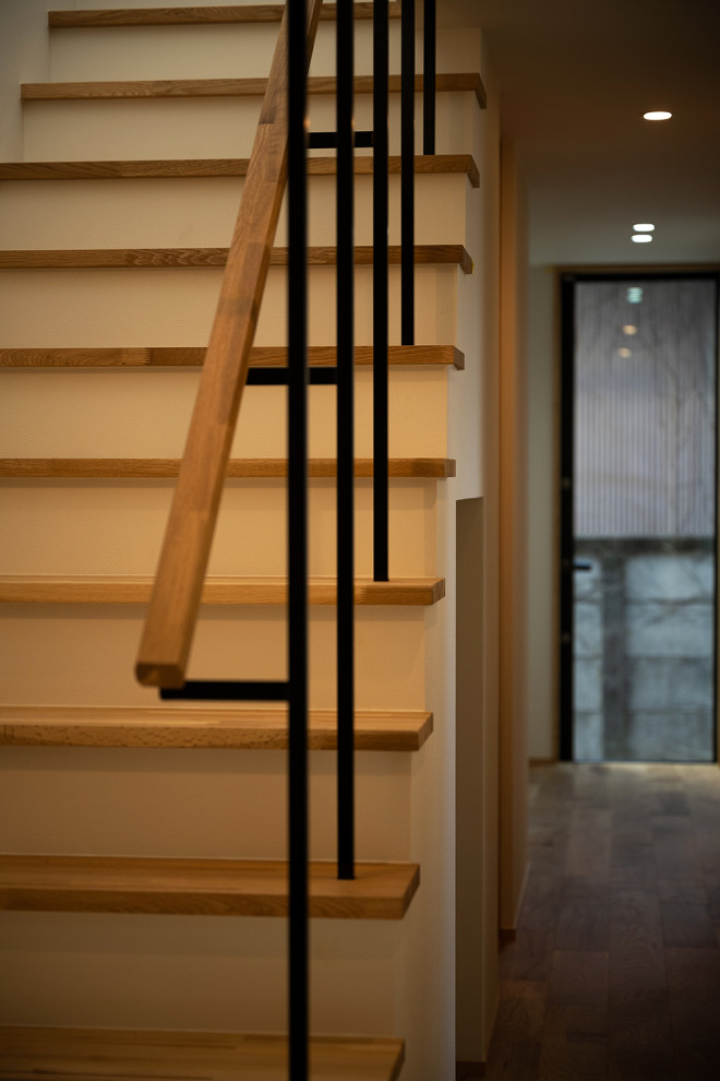На фото: прямая лестница среднего размера в скандинавском стиле с деревянными ступенями, металлическими перилами, обоями на стенах и кладовкой или шкафом под ней