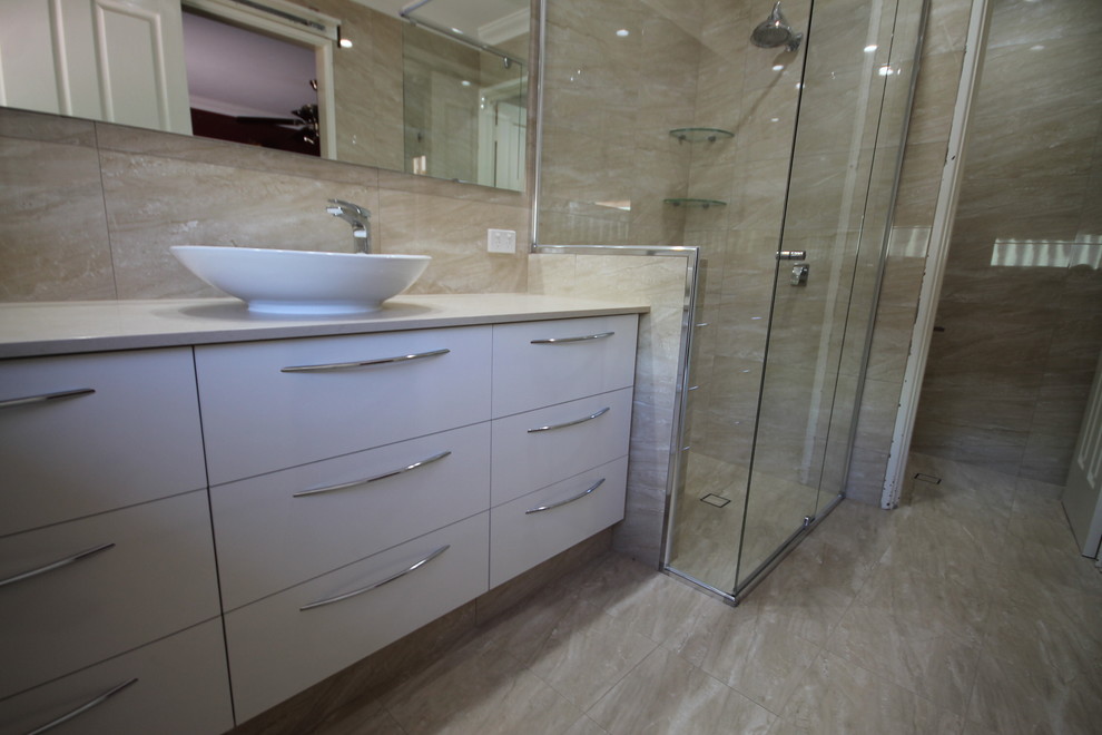 Idee per una stanza da bagno design di medie dimensioni con ante lisce, ante bianche, piastrelle beige, lavabo a bacinella e top in quarzo composito