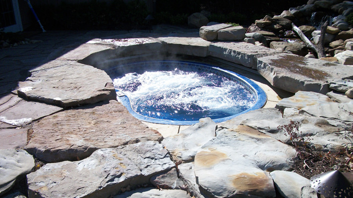 Large transitional backyard concrete paver and kidney-shaped hot tub photo in Chicago