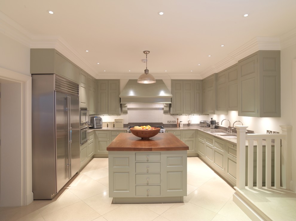 Photo of a large traditional kitchen in Other with an undermount sink, raised-panel cabinets, green cabinets, limestone benchtops, white splashback, stainless steel appliances, limestone floors and with island.