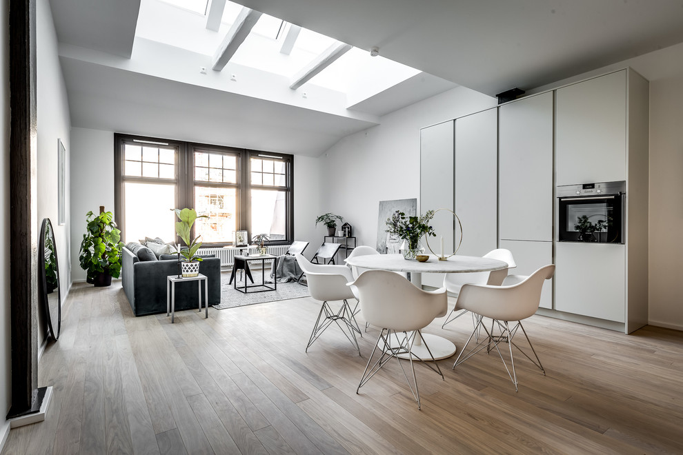 This is an example of a mid-sized scandinavian open plan dining in Stockholm with white walls, light hardwood floors and beige floor.
