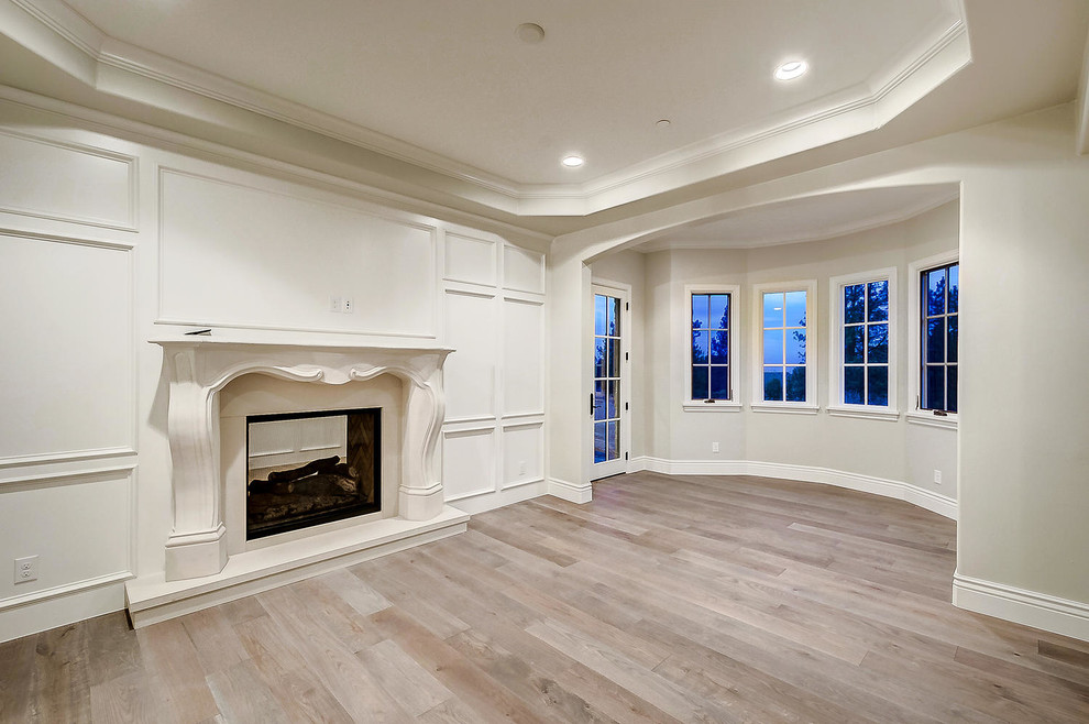 This is an example of a mid-sized enclosed family room in Denver with grey walls, light hardwood floors, a standard fireplace, a stone fireplace surround, no tv and brown floor.