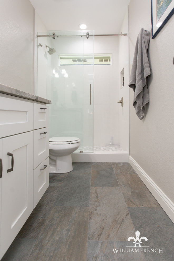 This is an example of a small transitional kids bathroom in Dallas with shaker cabinets, white cabinets, an alcove shower, gray tile, porcelain tile, grey walls, porcelain floors, an undermount sink, granite benchtops, grey floor, a sliding shower screen, grey benchtops, a niche, a single vanity and a built-in vanity.